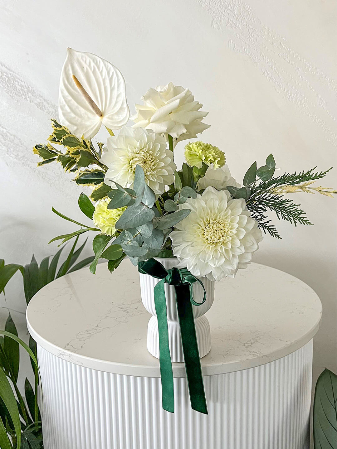 Stunning white and green table arrangement finished with holly and velvet ribbon. 