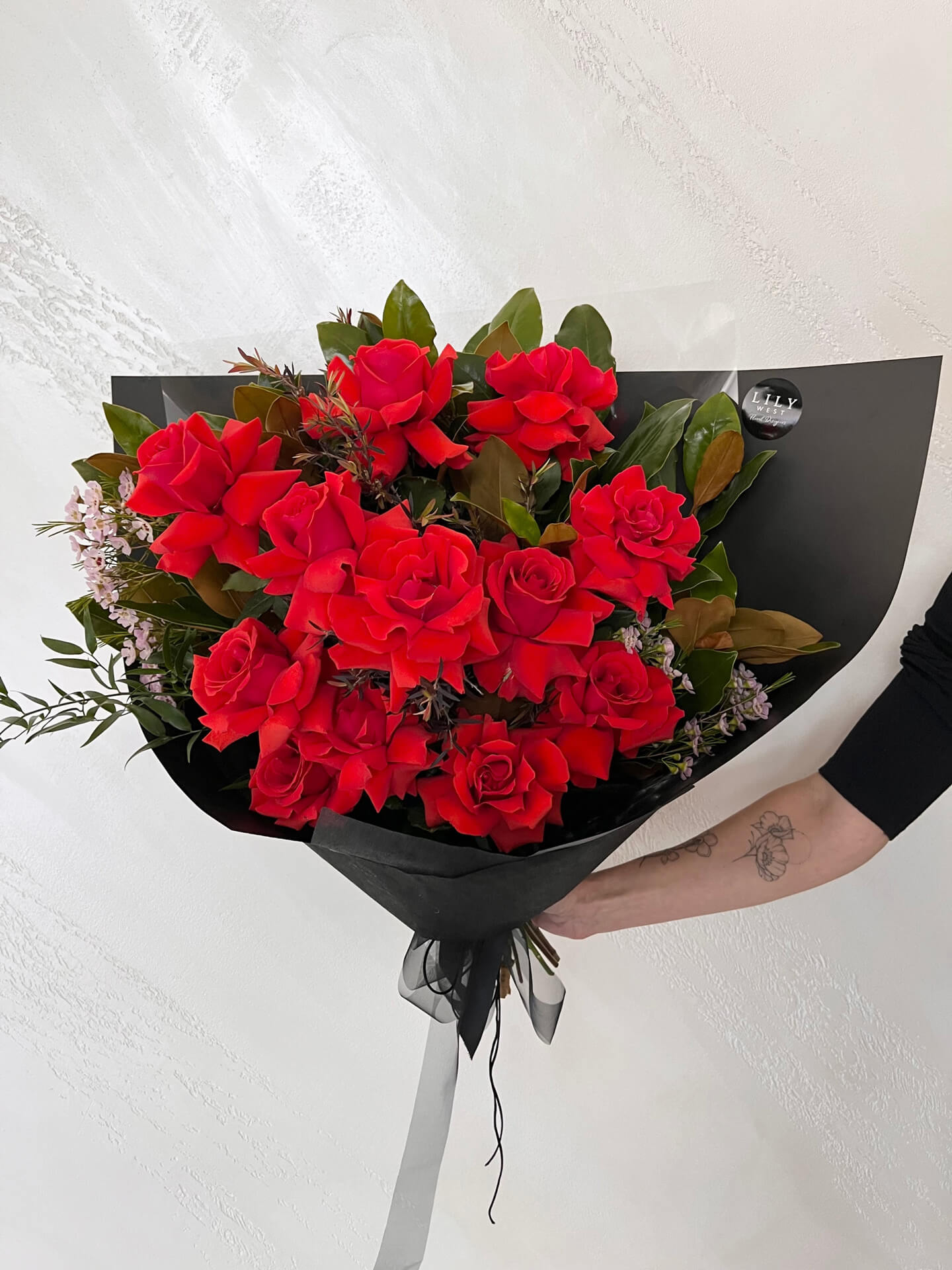 Bouquet of dozen (12) premium red roses and foliage wrapped and finished with ribbons.