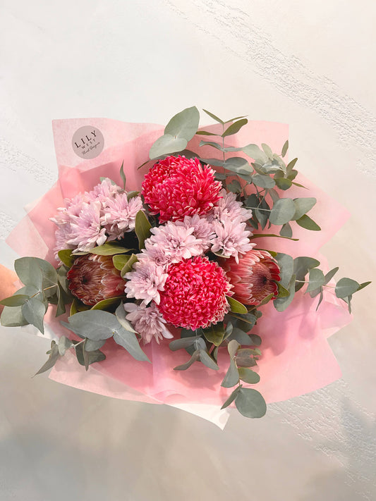 A bouquet featuring locally grown pink ice proteas, mums, daisies and blue gum, beautifully wrapped and hand tied with ribbon. 