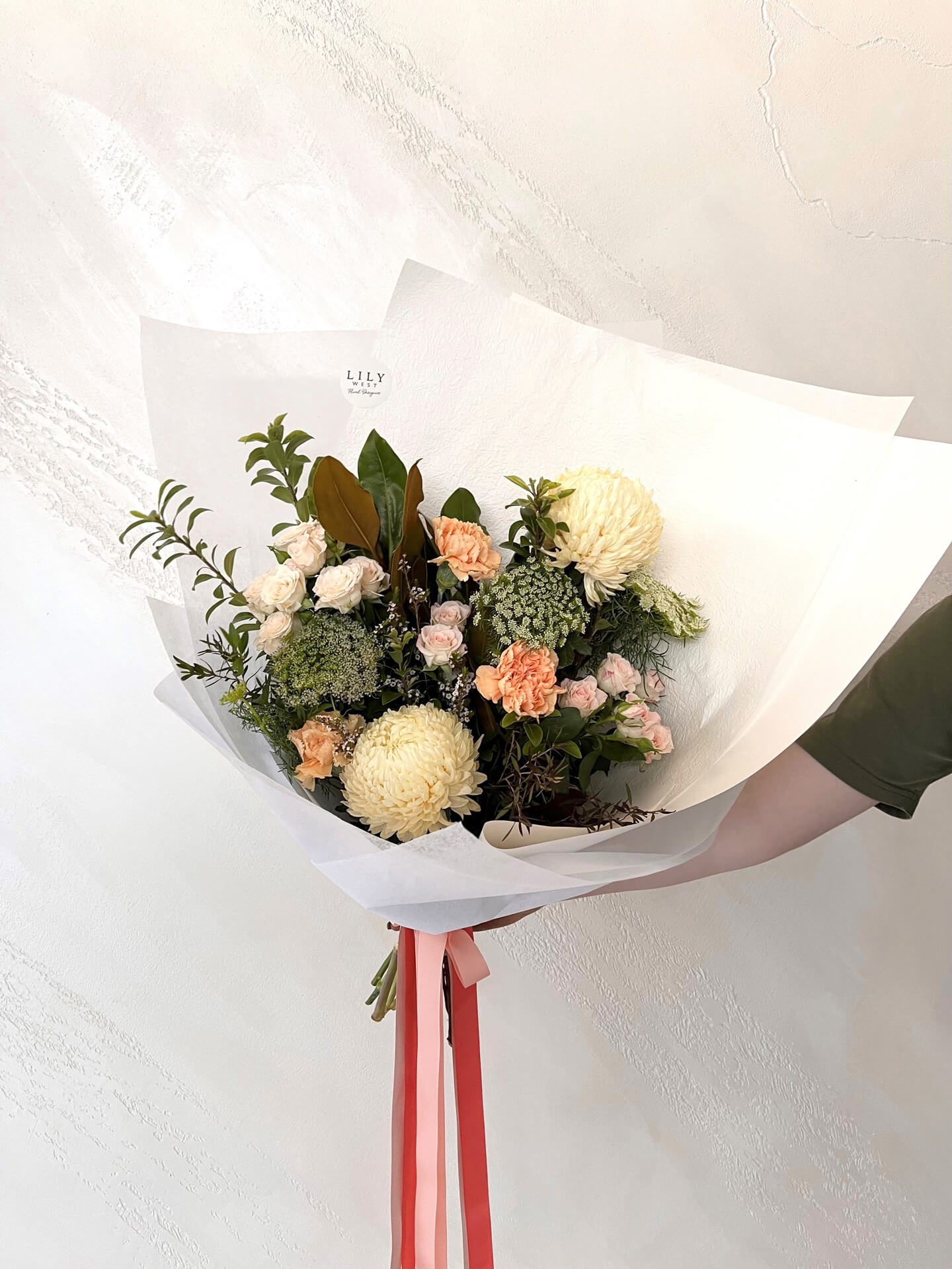 A bouquet with tones of apricot and peach using beautiful seasonal blooms. Each bouquet is designed and hand tied by our talented florists and finished with luxurious white wrap and a ribbons to compliment.&nbsp;